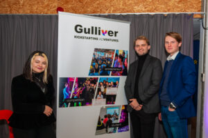 Three of our guests at the Gulliver Grande Finale in front of a company banner